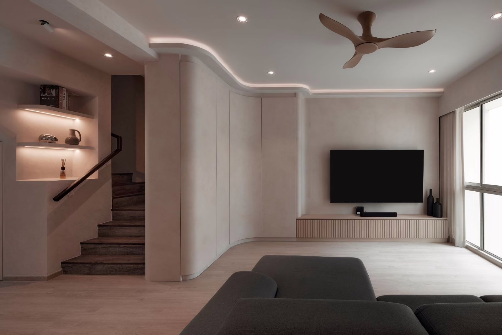 Modern living room in BLK 4 Bedok Reservoir View, featuring a curved wall unit and dark gray sofa.